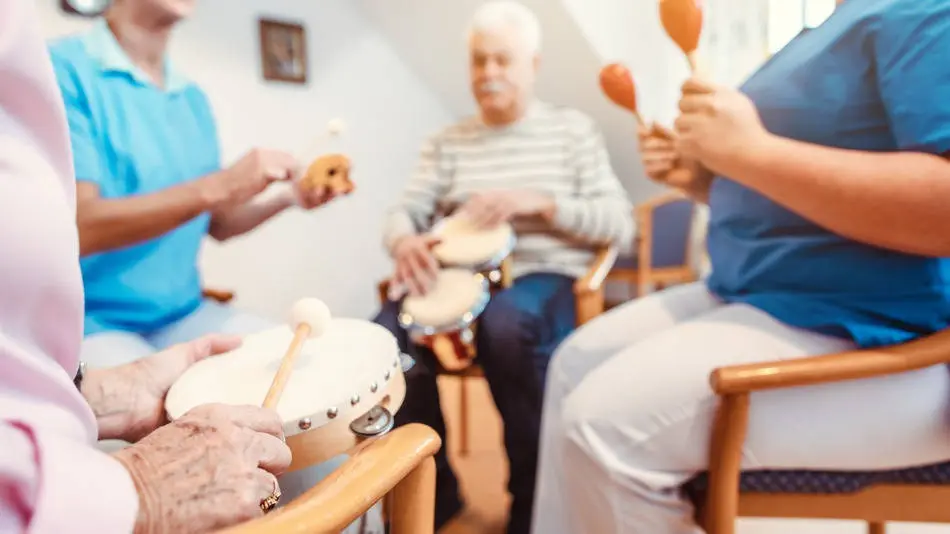 Grupo de adultos mayores cantando canciones y recordando letras en un ambiente de convivencia y alegría.