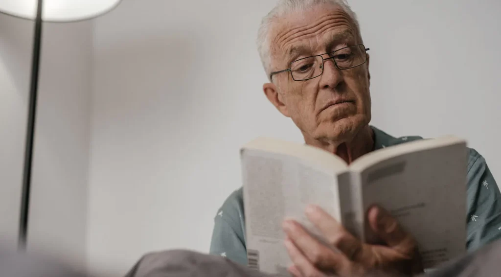 Adulto mayor leyendo un libro como parte de la estimulación cognitiva para adultos mayores para fortalecer la memoria y la comprensión.